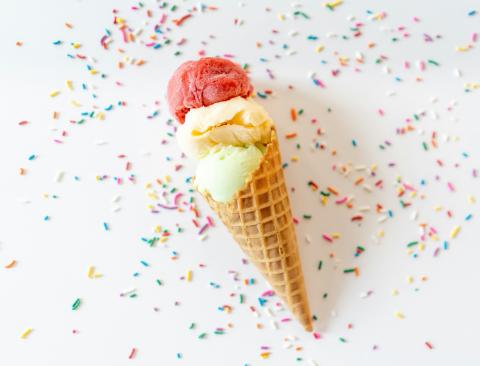 A two-scoop ice cream cone surrounded by multicolored sprinkles